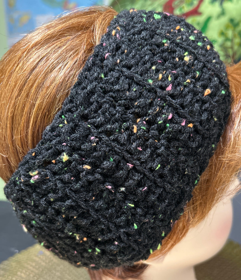Black knitted headband with colorful speckles worn by a person with red hair.