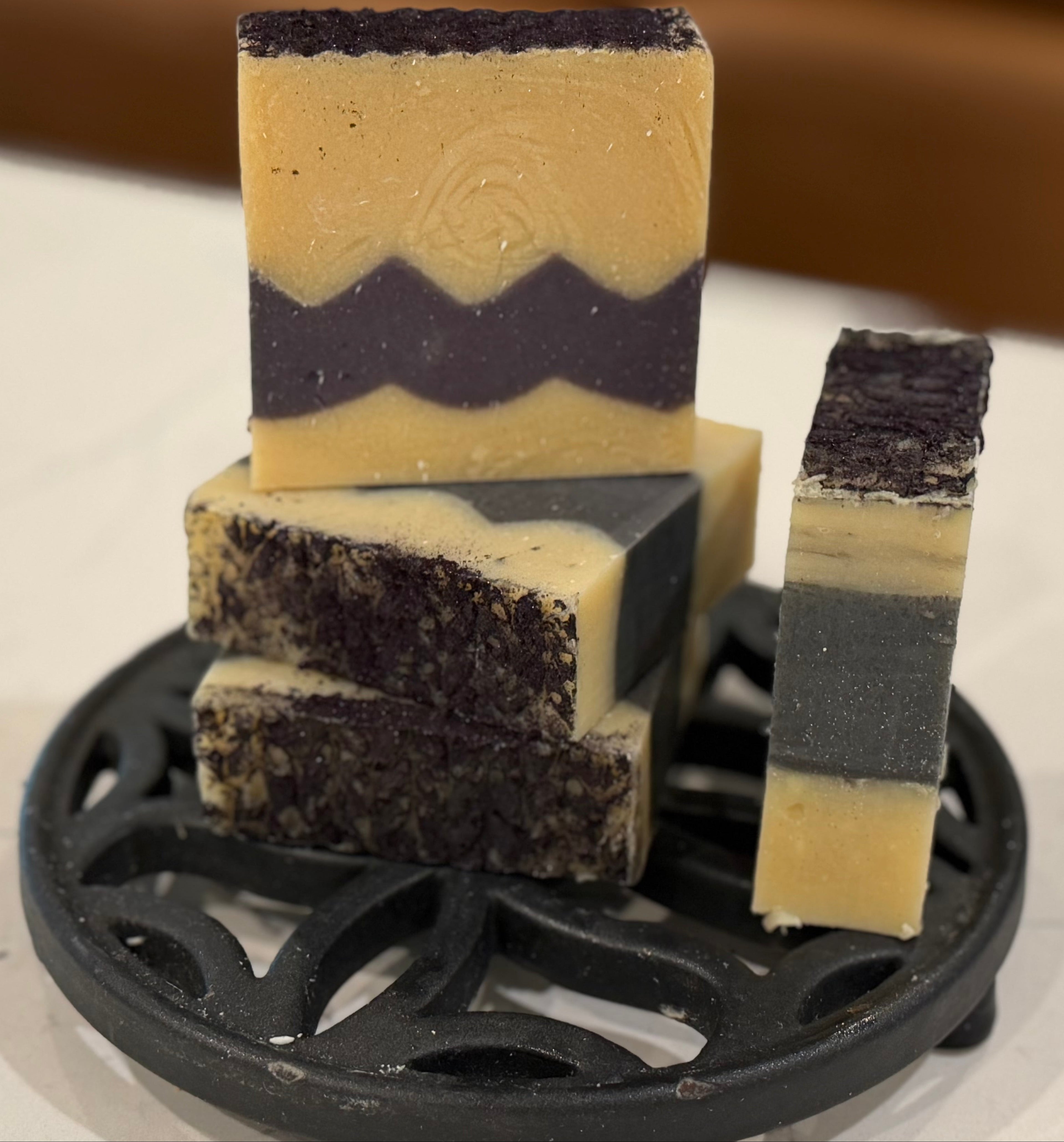 Three bars of soap with a wavy pattern on a black decorative stand.