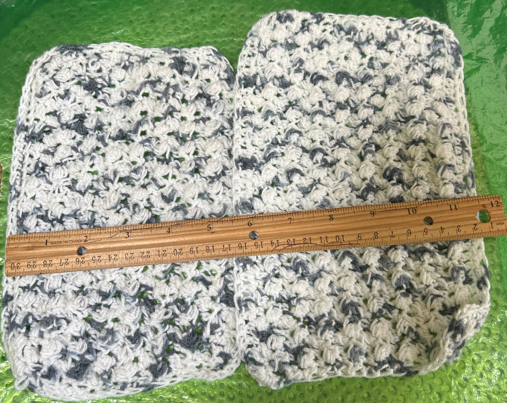 Two stone-like fabric swatches with a ruler for scale on a green surface.