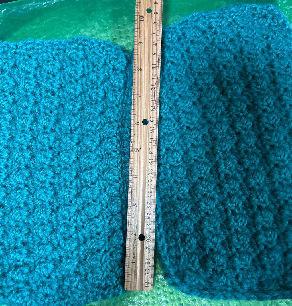 Teal textured fabric with a wooden ruler for scale on a green background