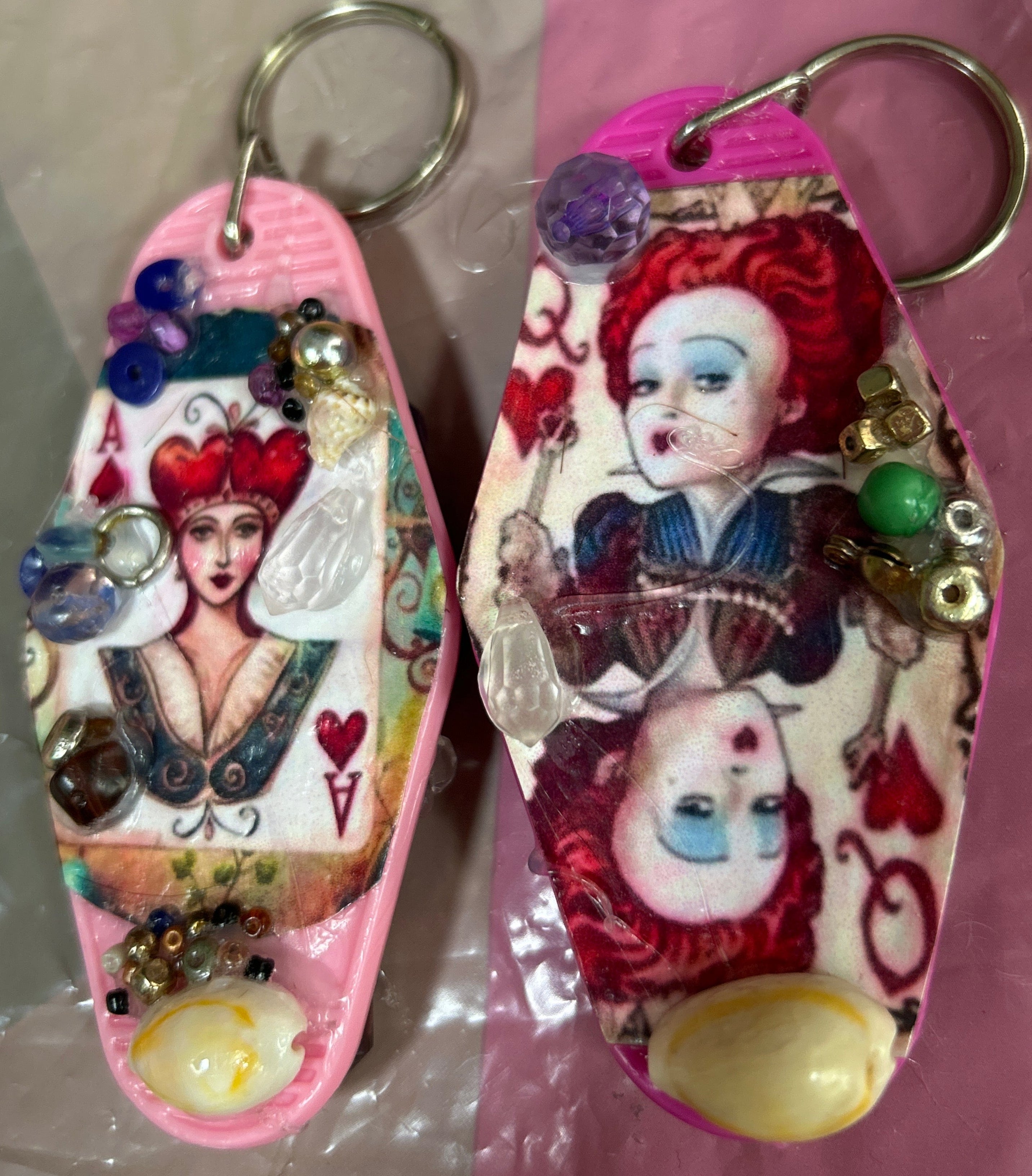 Two decorative keychains with cartoon character designs on a pink and white background.