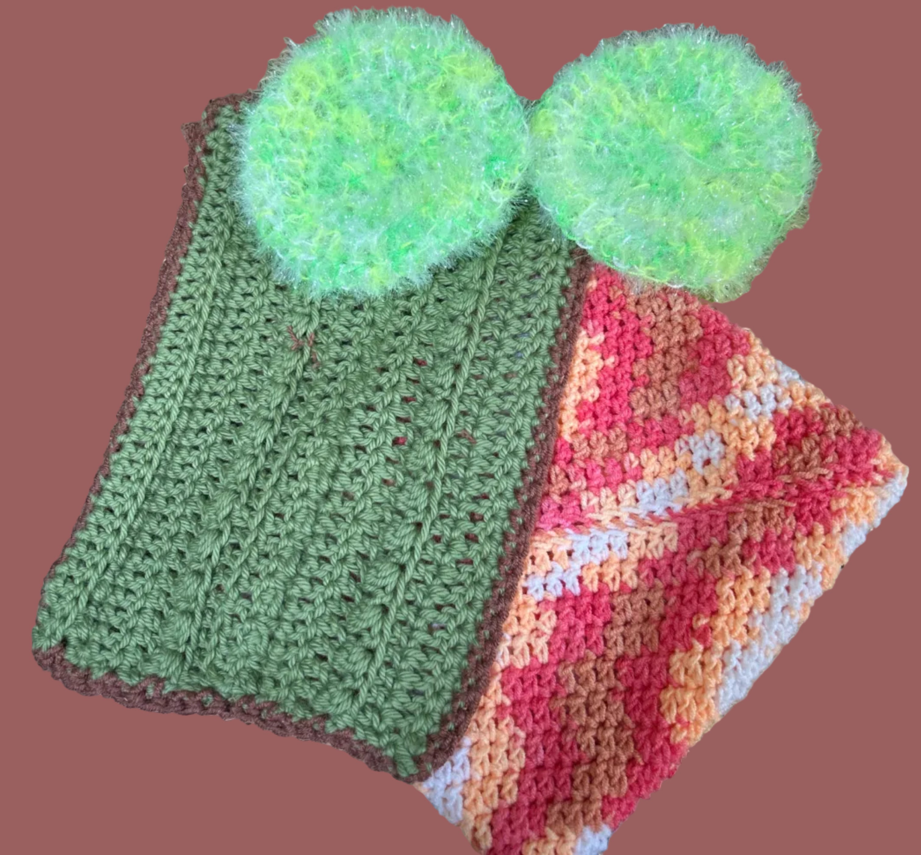 Knitted items including a green hat and colorful scarf on a metallic surface.