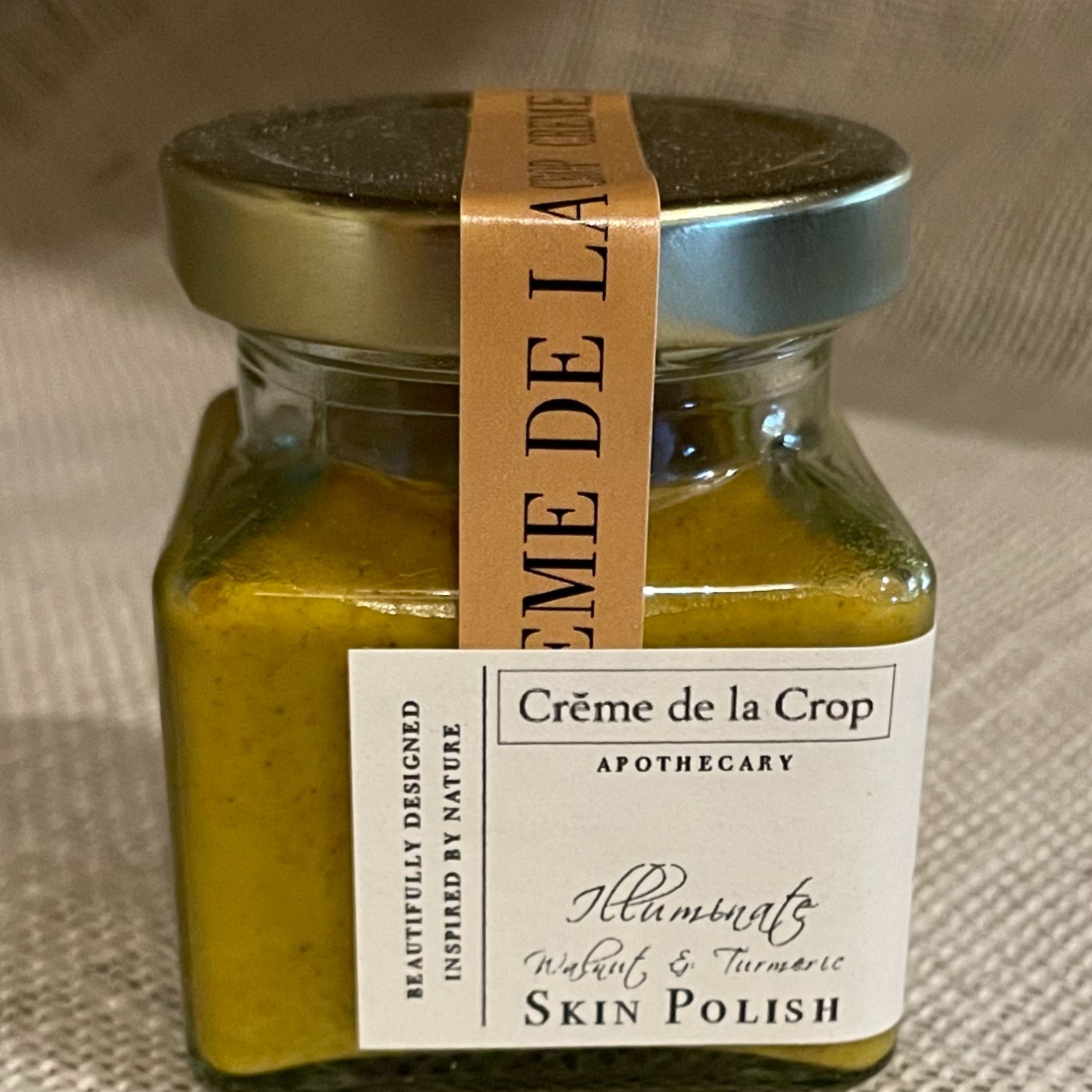 Jar of 'Cème de la Crop' skin polish on a textured fabric background