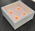 Square fire pit with glowing candles on a wooden surface