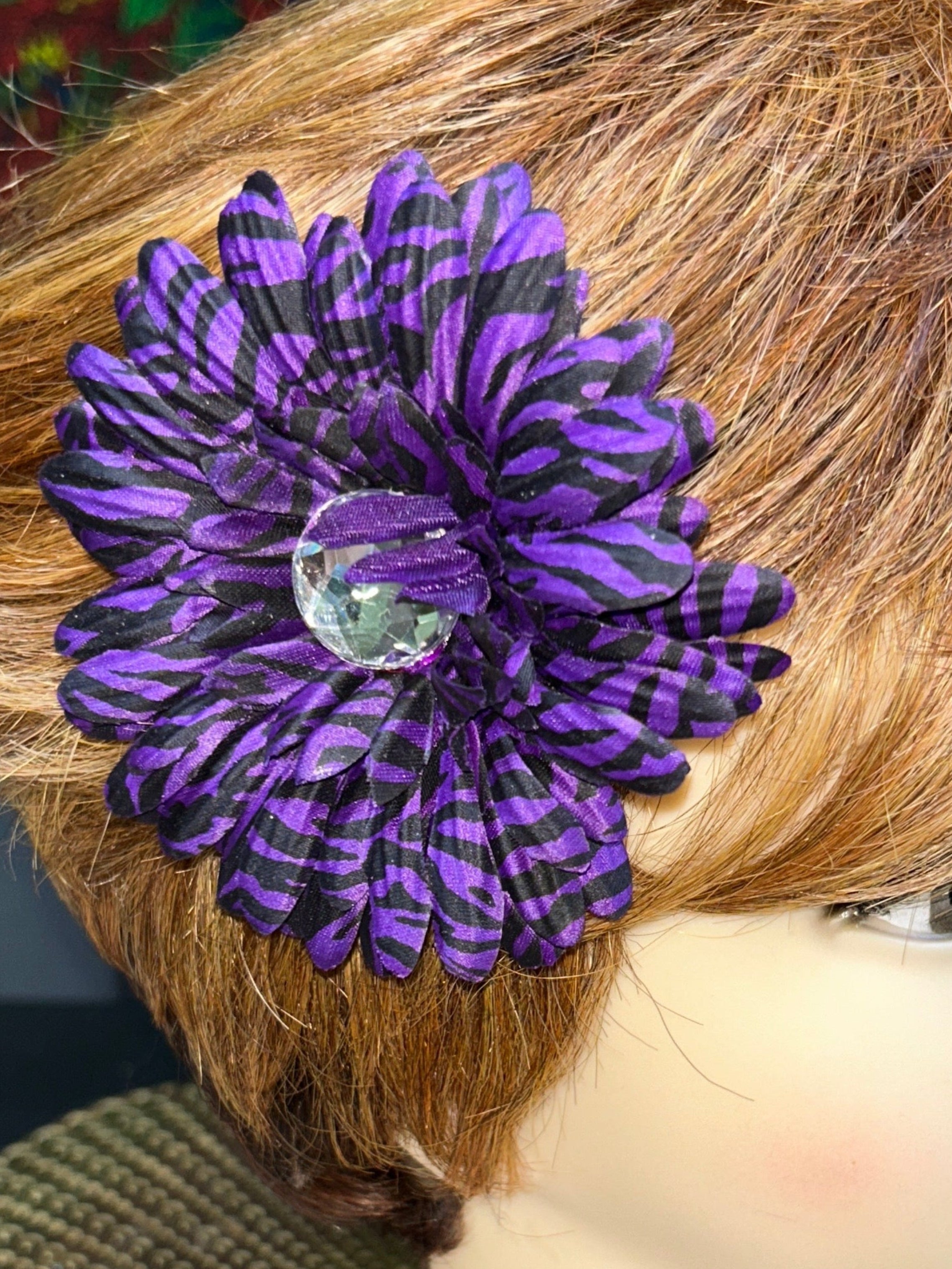 Mannequin head with a purple flower accessory and a decorative hat.