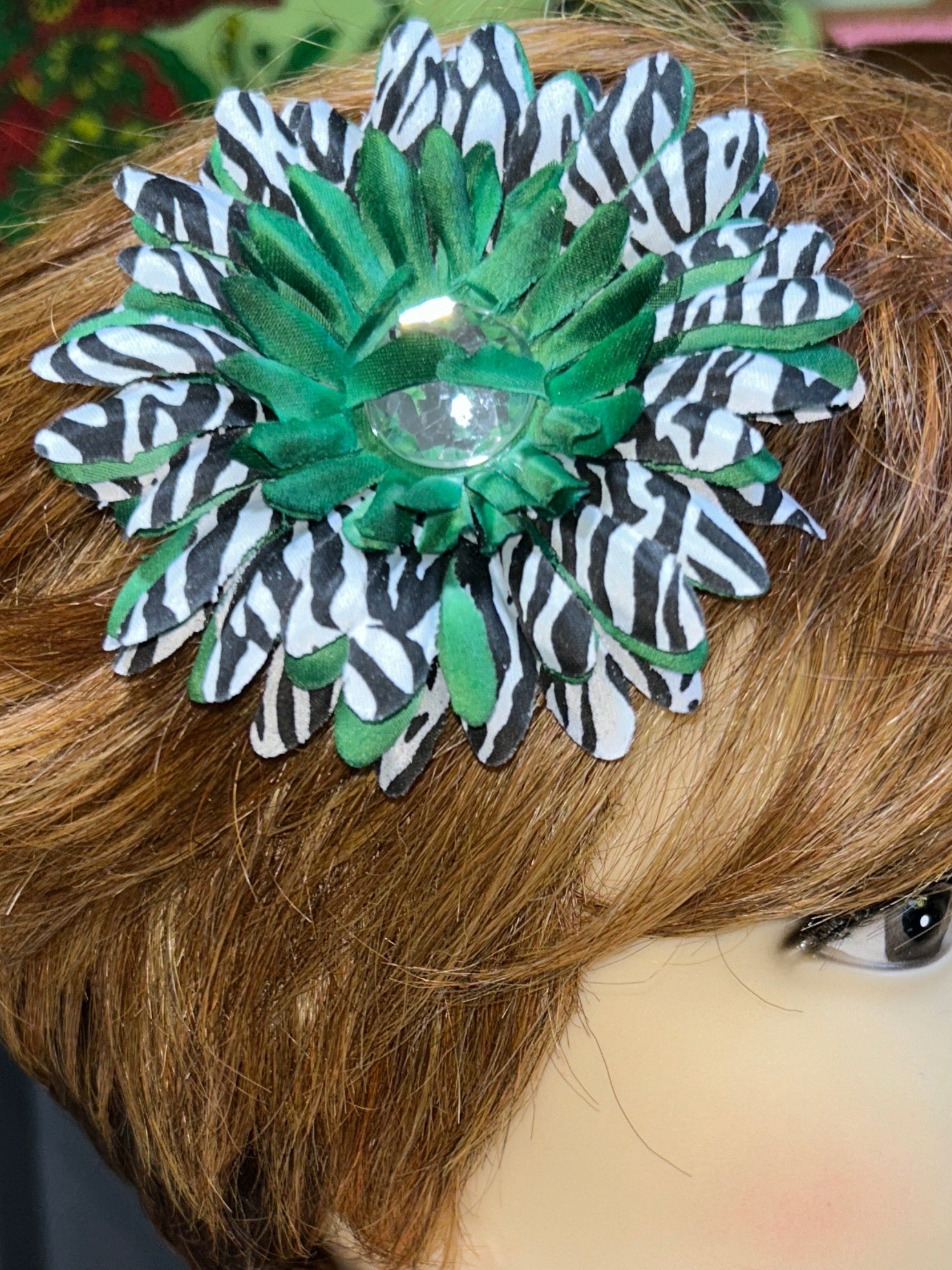 Mannequin head with a green and black flower accessory on a blurred background