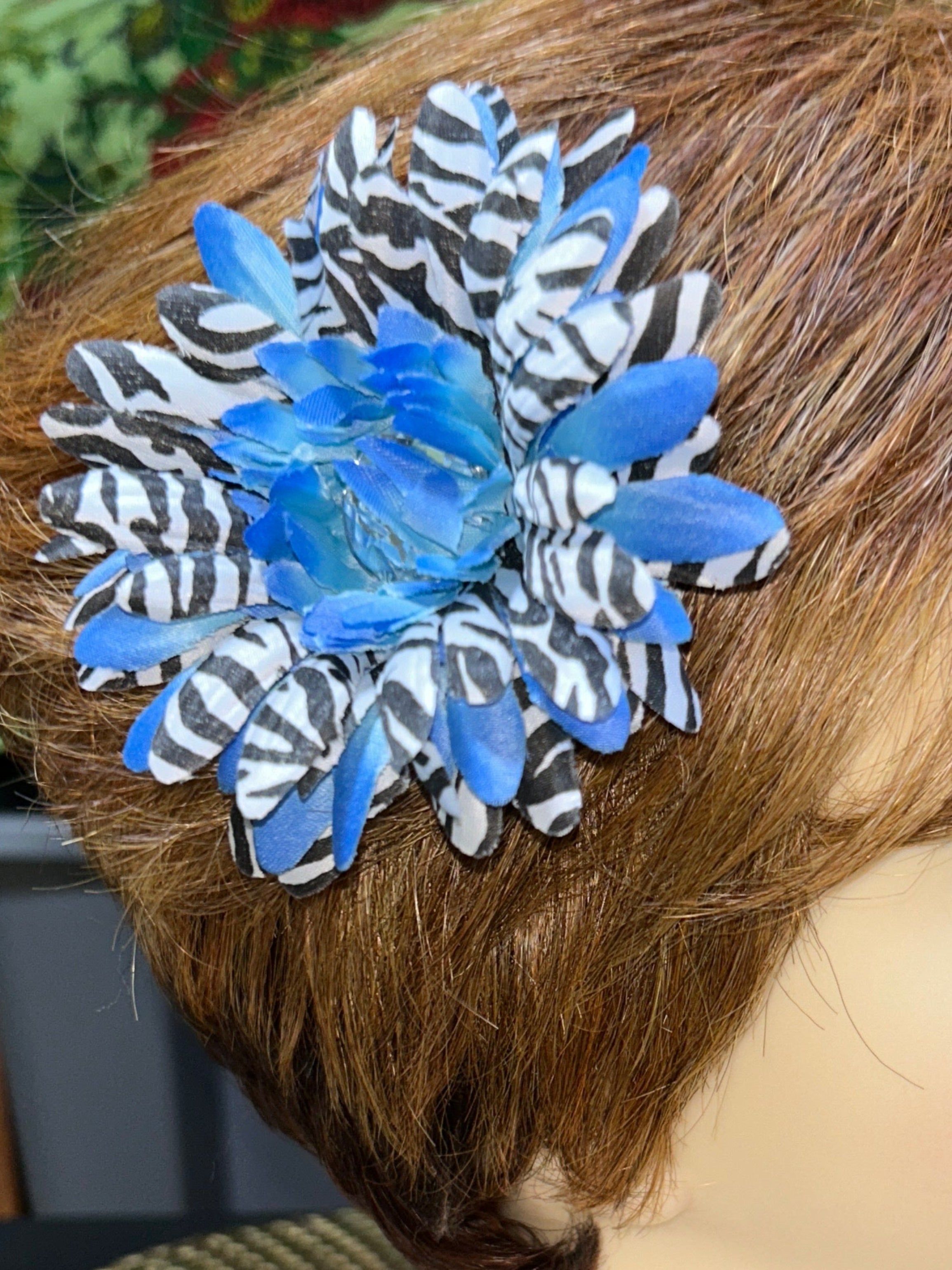 Mannequin head with brown hair styled with a blue and silver decorative hair clip.