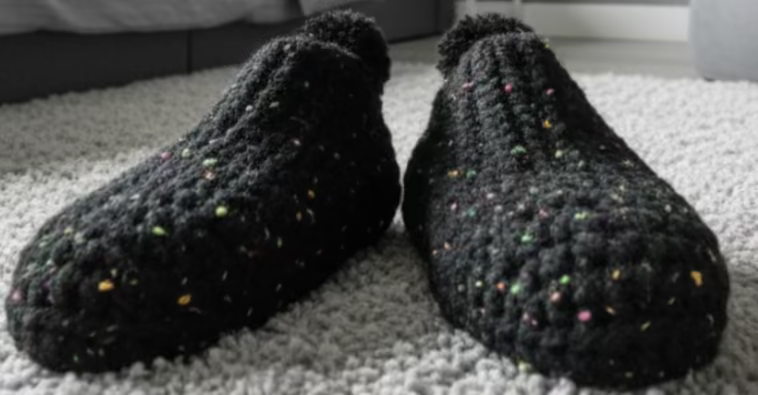 Pair of black textured slippers on a pink and white striped surface