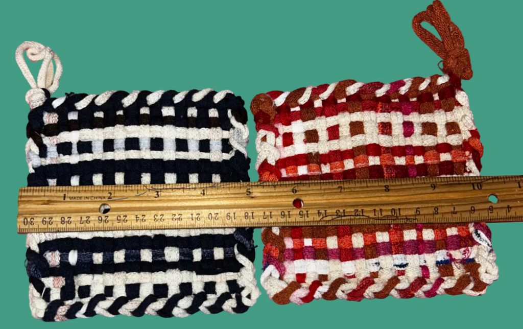 Two small potholders, one black and white striped and one red and white checkered, with a ruler for scale on a pink background.