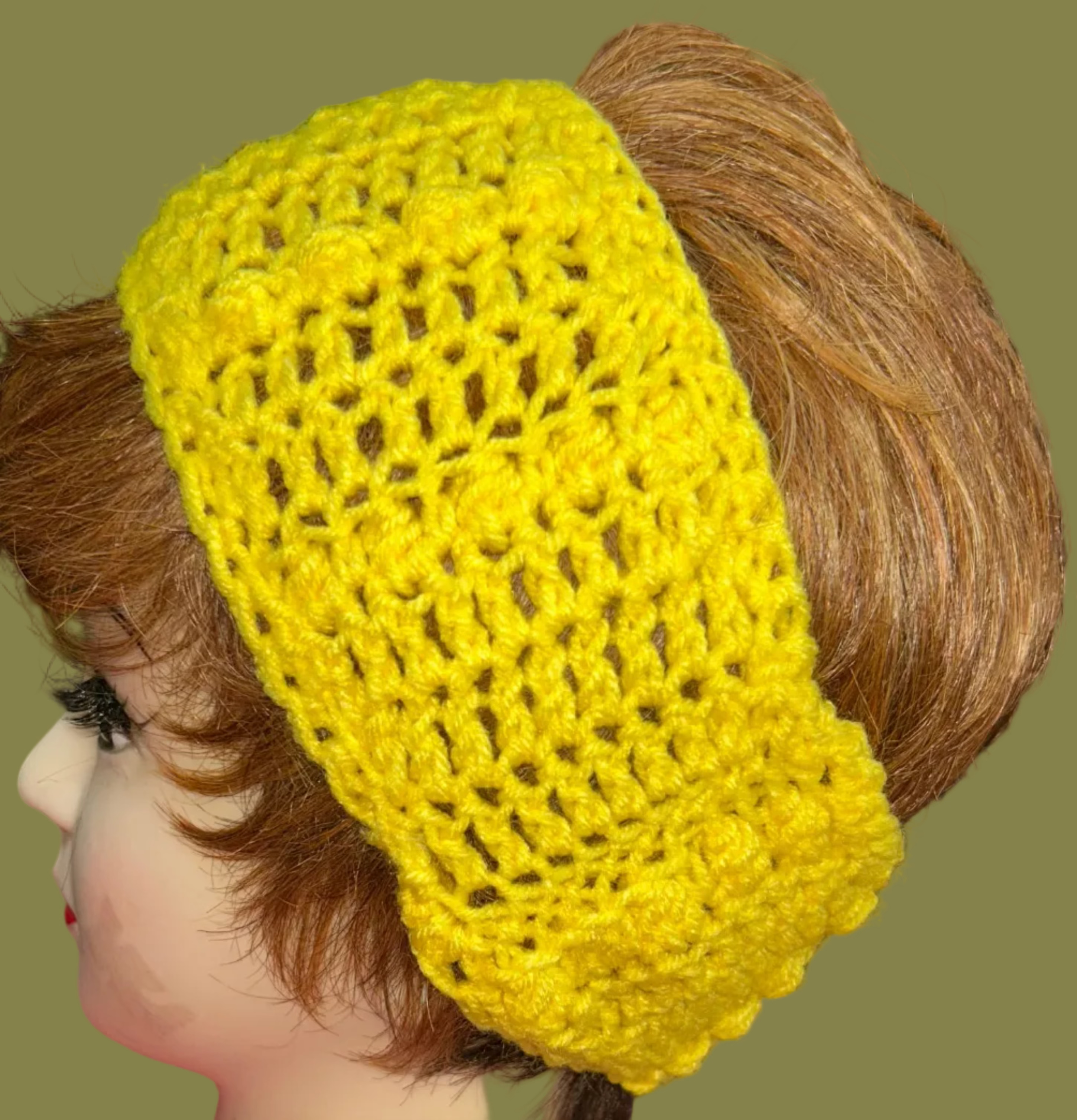 Yellow crocheted headband on a mannequin head with a blurred indoor background