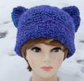 Blue crocheted cat ear hat on a mannequin head with a colorful background
