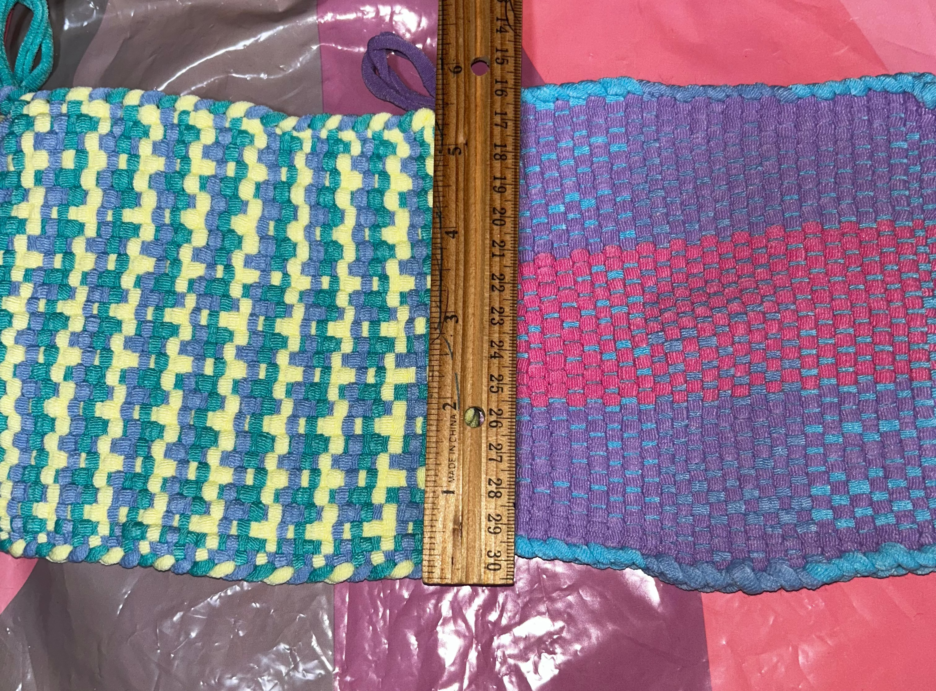 Colorful woven potholders with a ruler for scale on a multicolored background