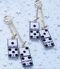 Pair of earrings with domino-like designs on a light blue background with star patterns.