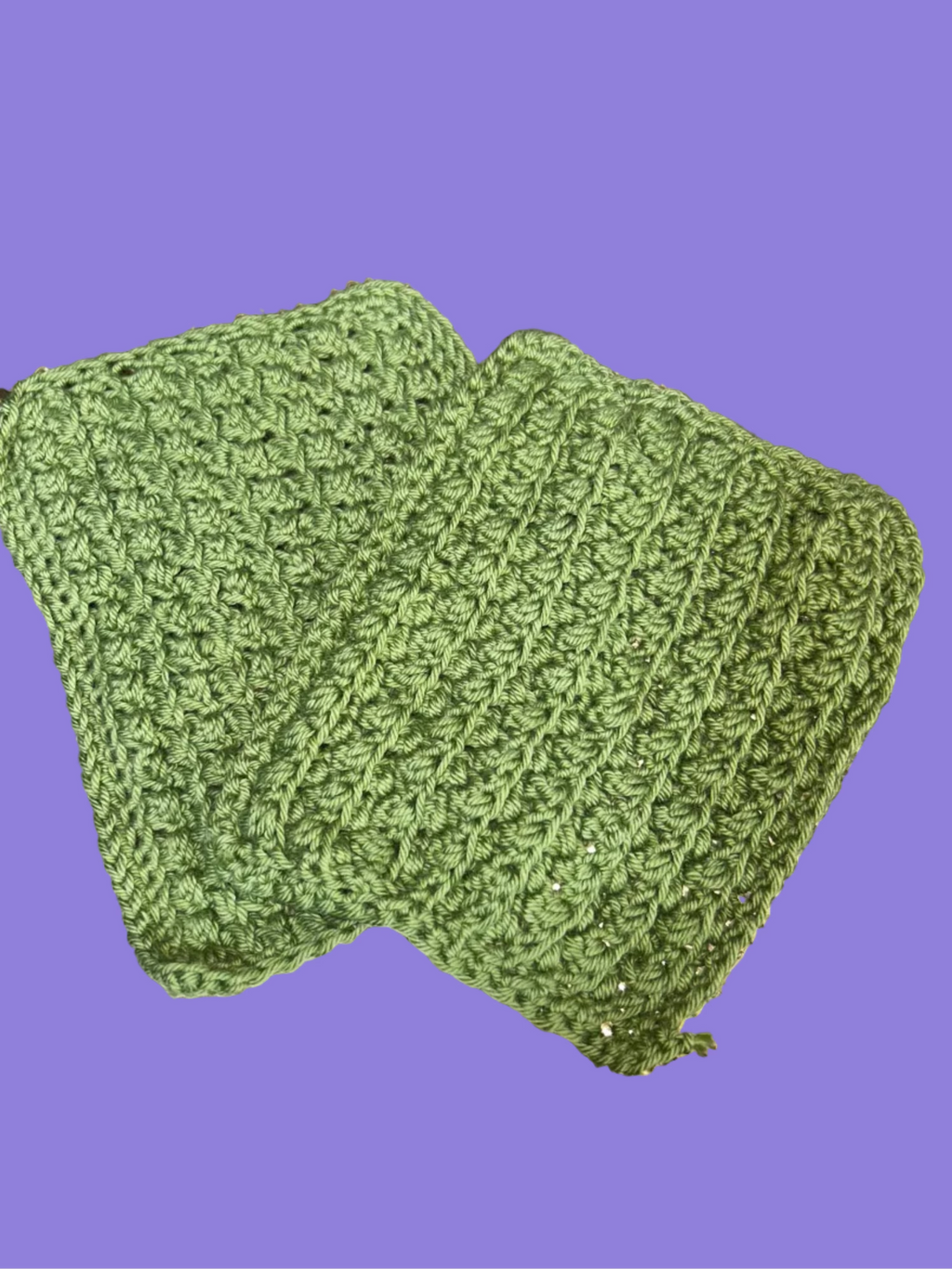 Two green crocheted dishcloths on a surface
