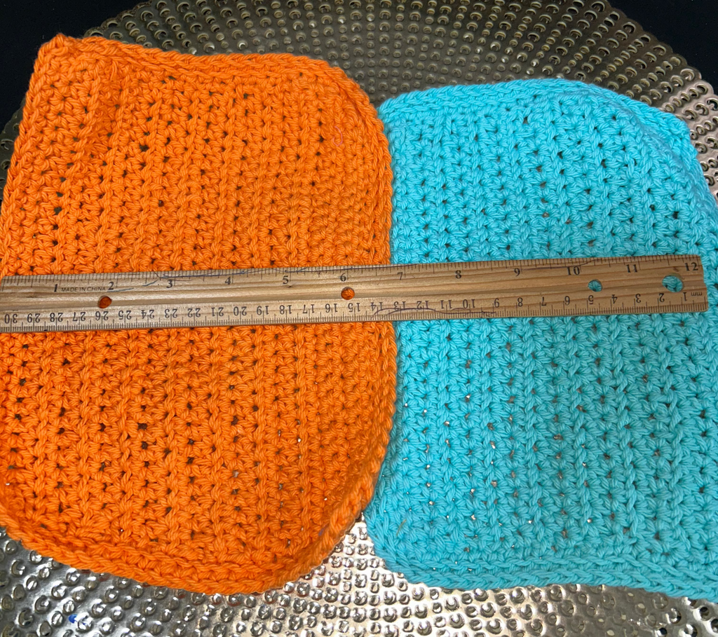 Two crocheted items, one orange and one blue, on a textured surface with a ruler for scale.
