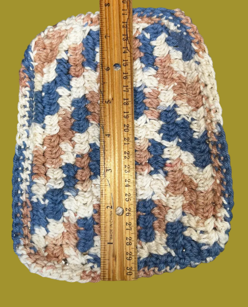 Crocheted item with a ruler for scale on a textured surface