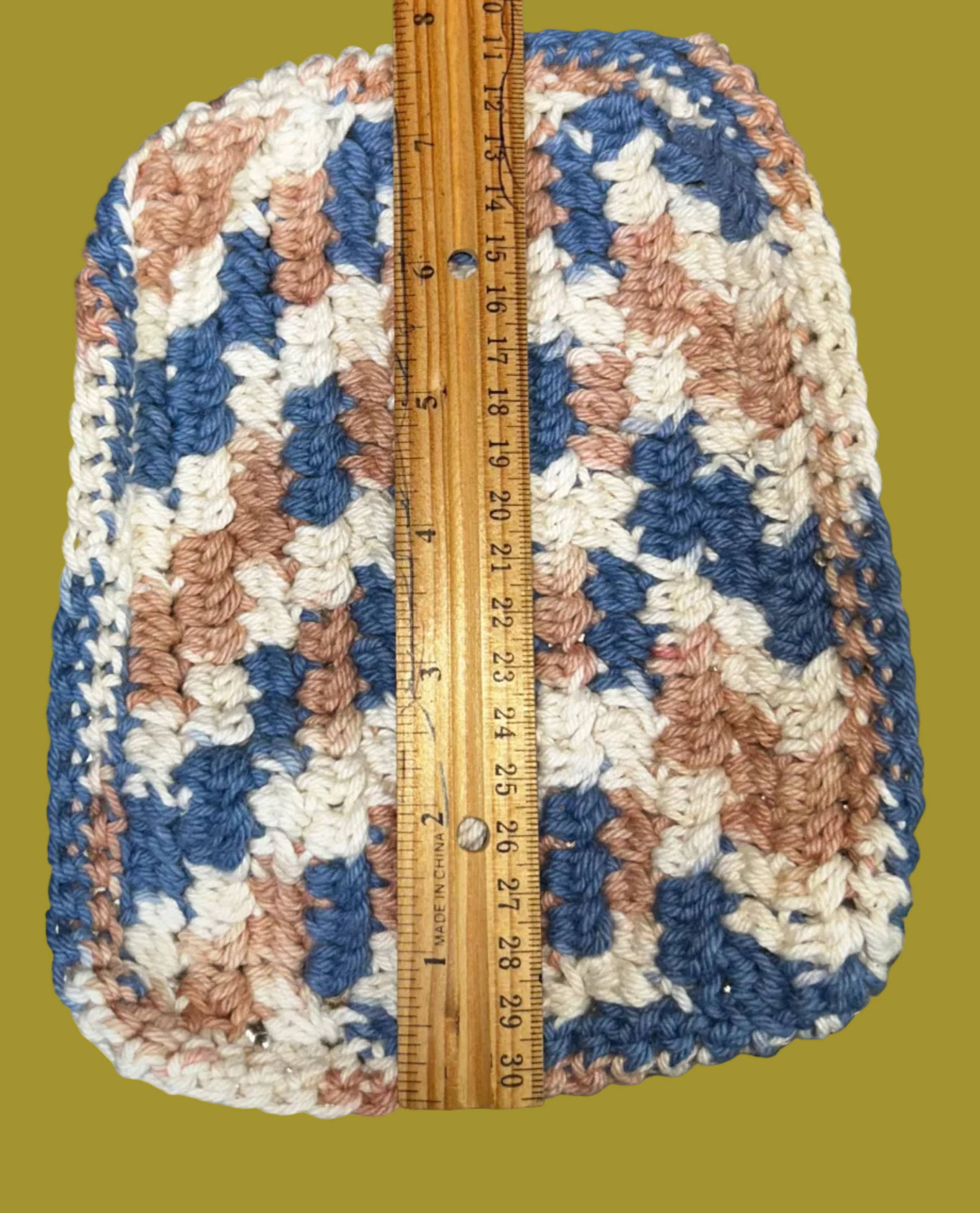 Crocheted item with a ruler for scale on a textured surface