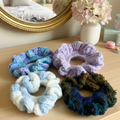 Set of colorful crocheted scrunchies on a textured surface