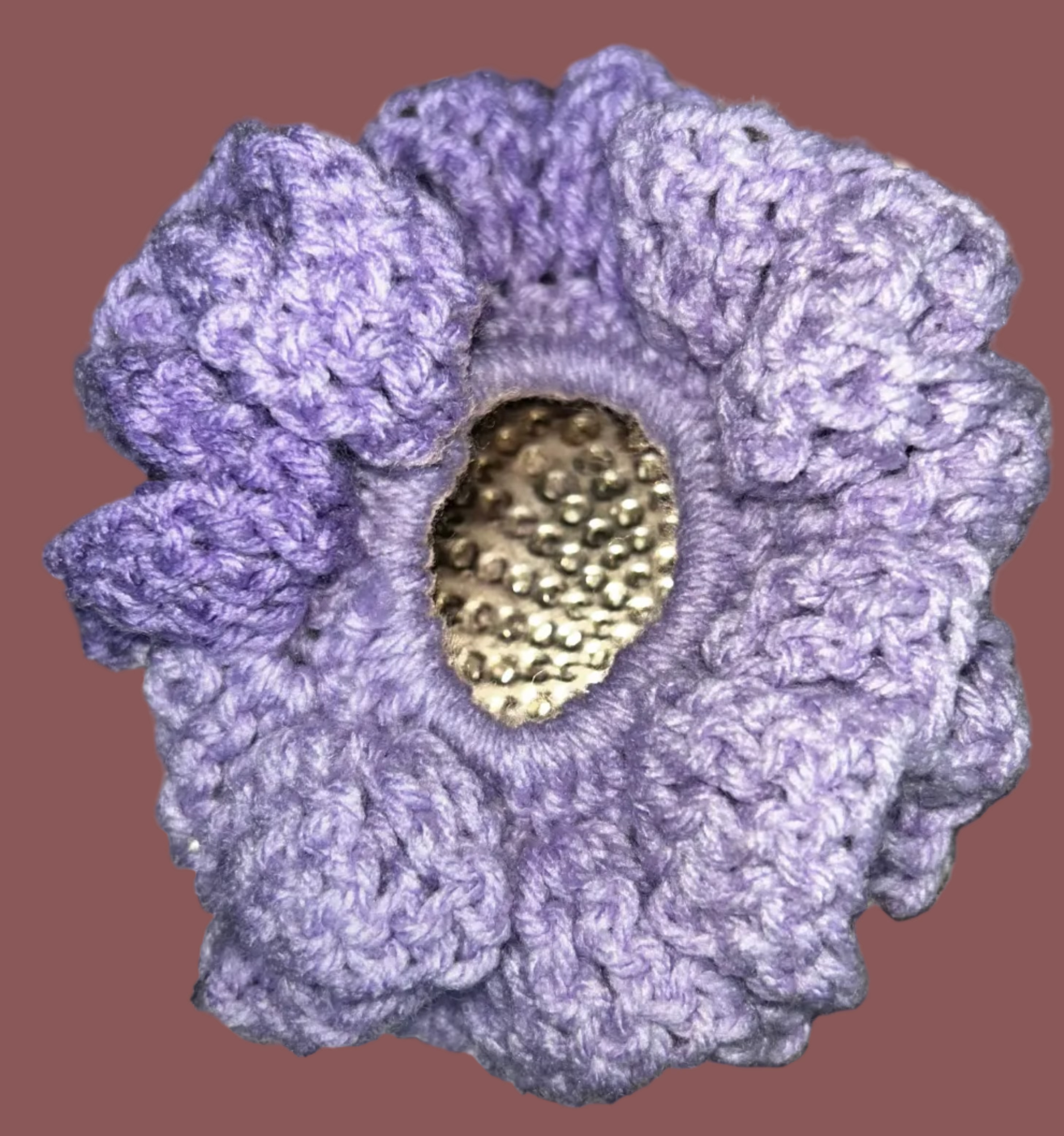 Purple crocheted scrunchie with a gold heart on a textured metallic background