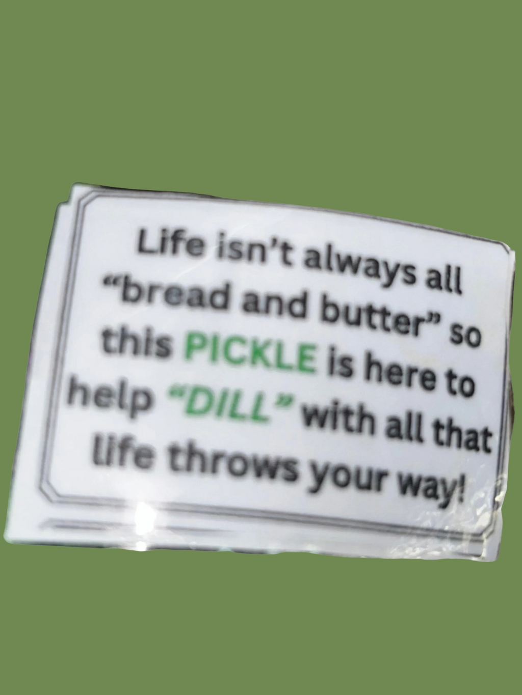 Green crocheted pickle with a humorous message on a textured gold background