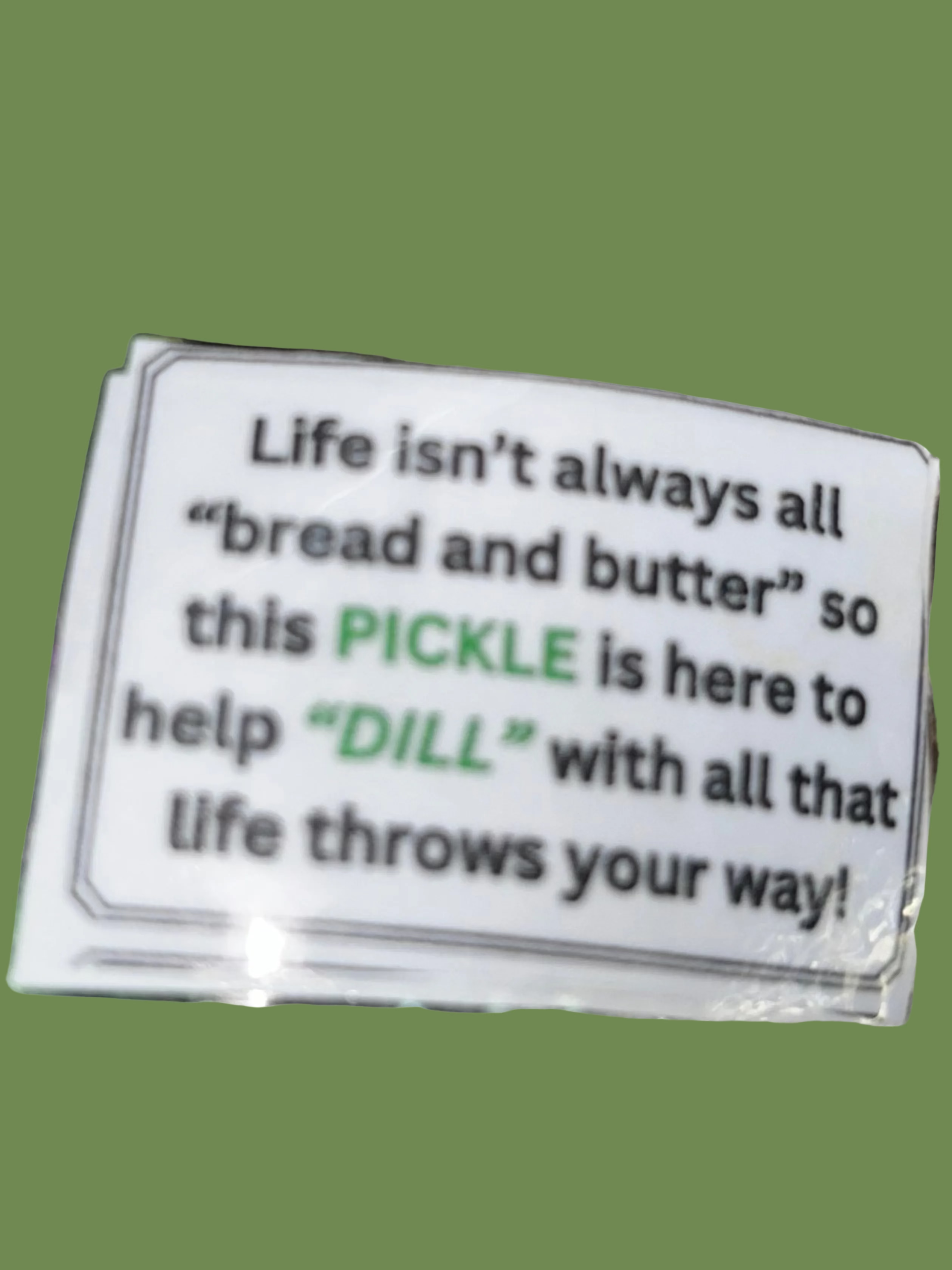 Green crocheted pickle with a humorous message on a textured gold background