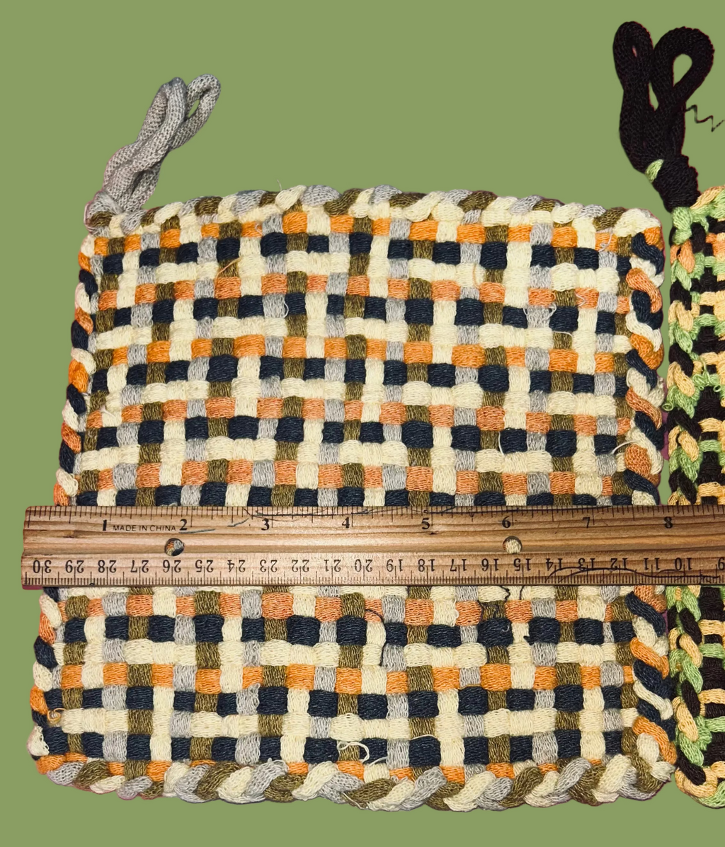 Plaid potholders with a ruler for scale on a green background