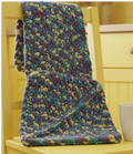 Colorful knitted blanket on a yellow surface with a white mug.