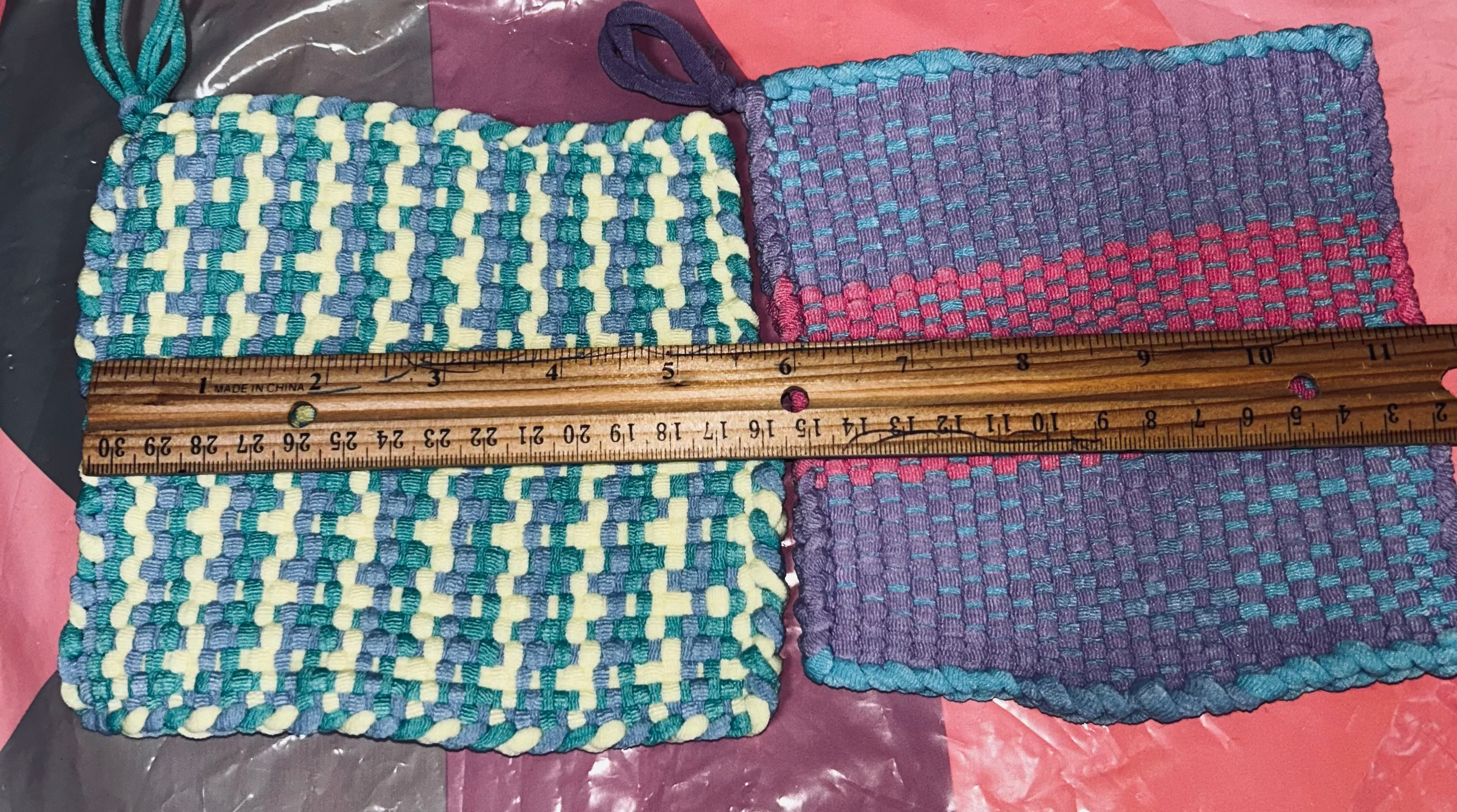 Two woven potholders with a ruler for scale on a colorful background