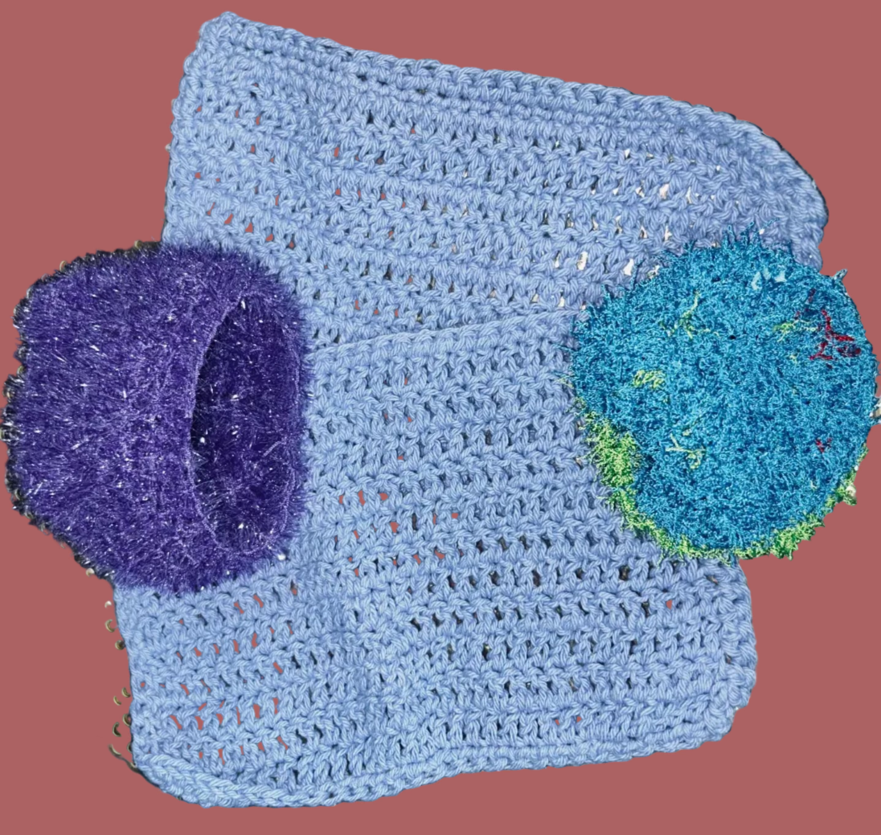 Blue crocheted item with purple and green accents on a textured surface