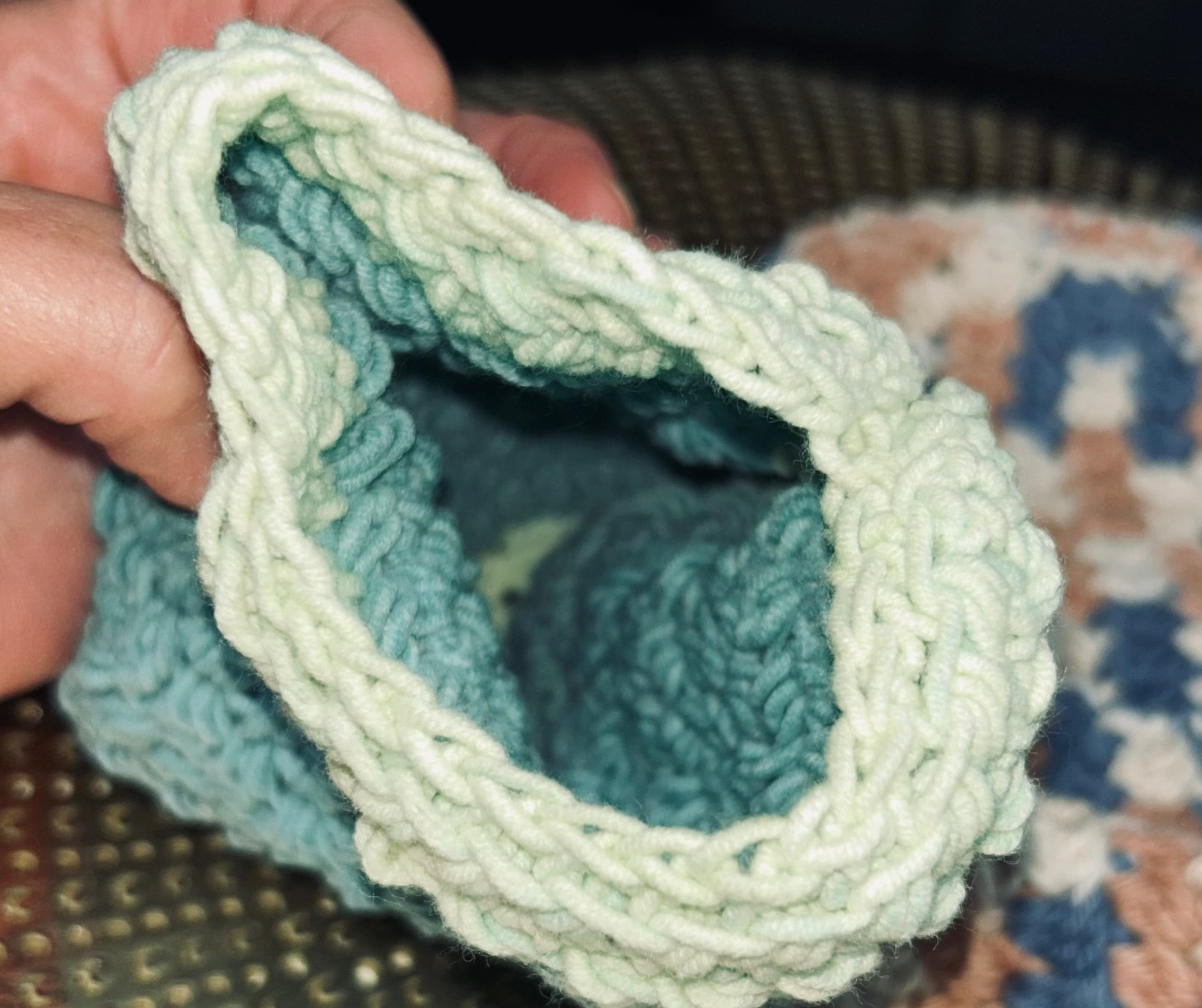 Hand holding a crocheted dishcloth with a textured surface in the background