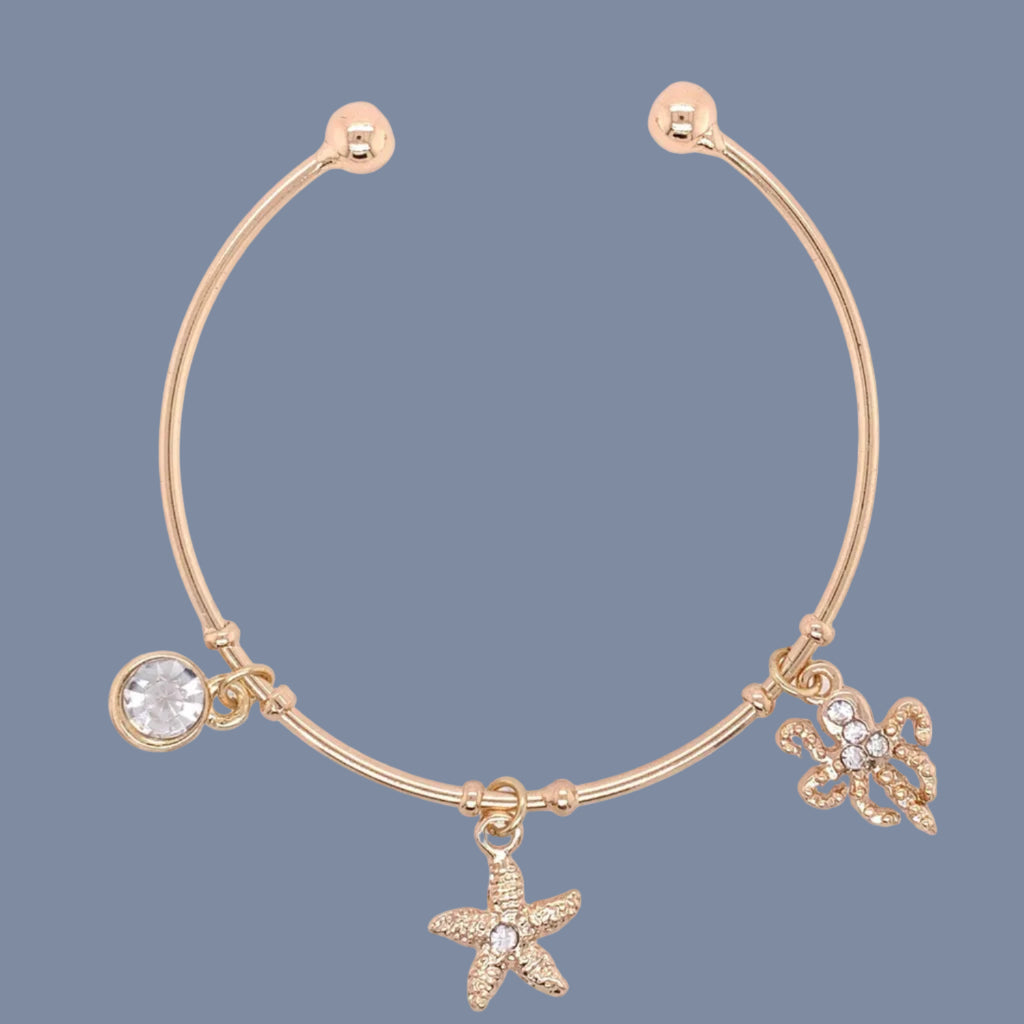 Gold bracelet with starfish and butterfly charms on a white background