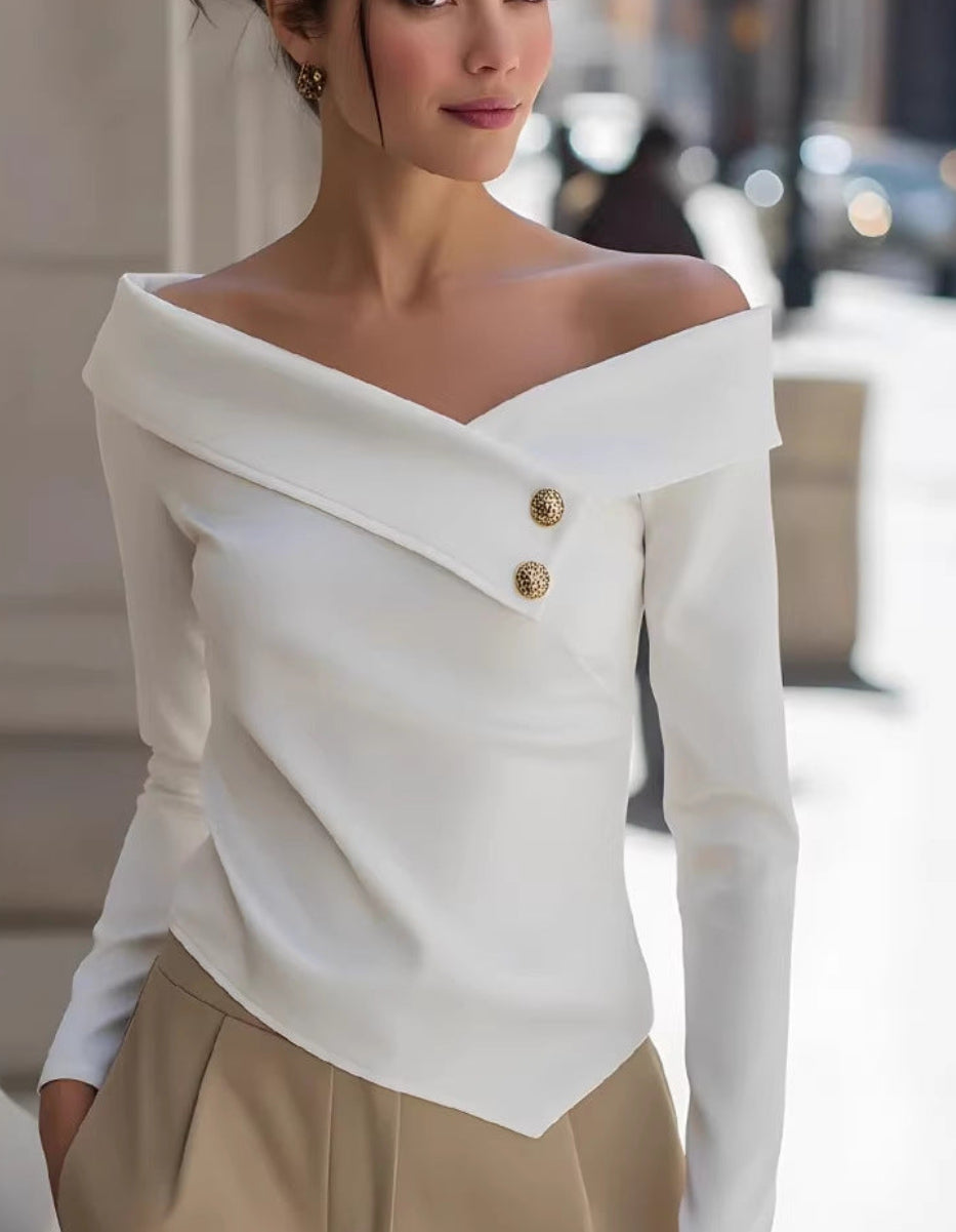 Woman wearing a white off-shoulder top with gold buttons and beige pants on a city street.