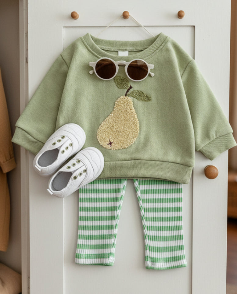 Green sweatshirt with pear design, white sneakers, and green checkered pants on a light gray background
