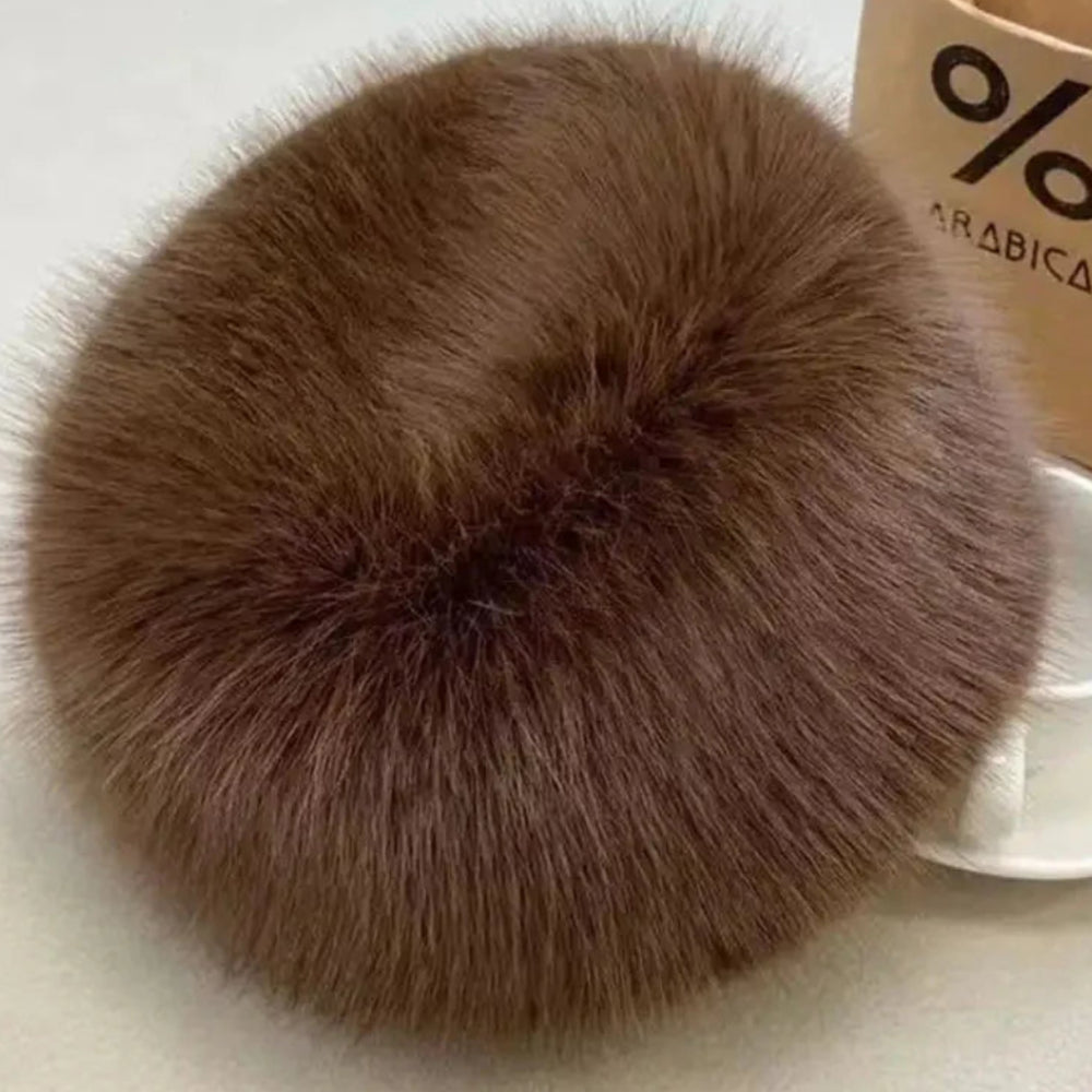 Brown fluffy item on a light surface with a coffee cup and 'Arabica' paper bag in the background.