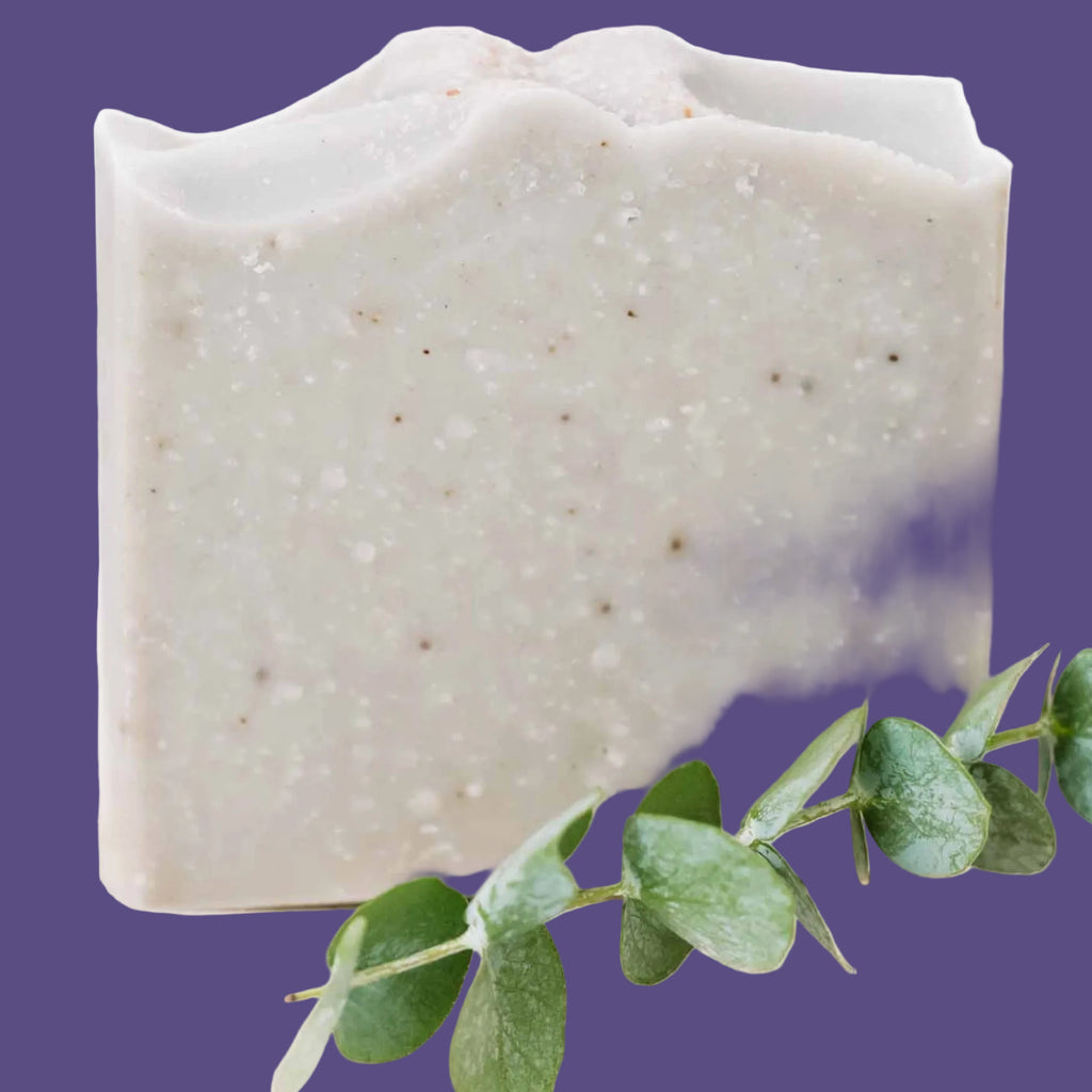 Square bar of soap with a green leaf on a white background
