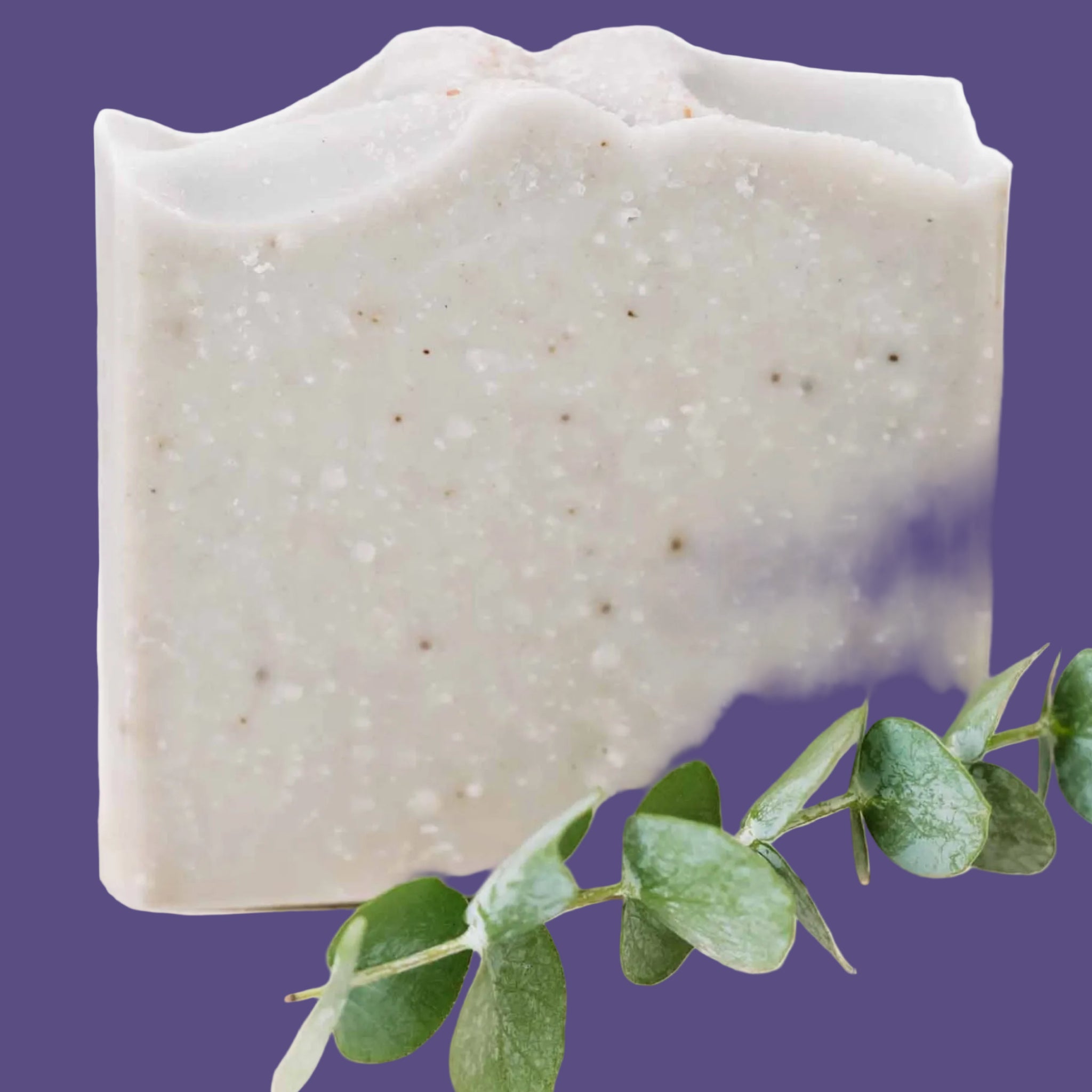 Square bar of soap with a green leaf on a white background