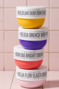Stack of four colorful cream jars with visible brand names on a white background