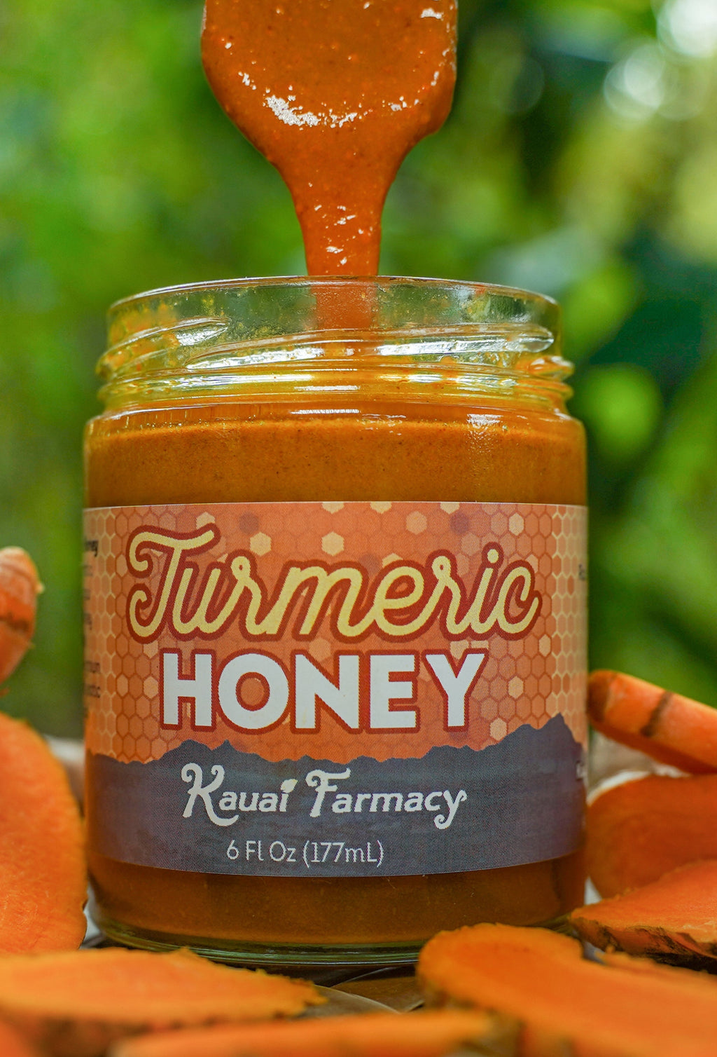 Jar of Turmeric Honey with a spoonful being lifted, surrounded by turmeric roots, against a natural background.
