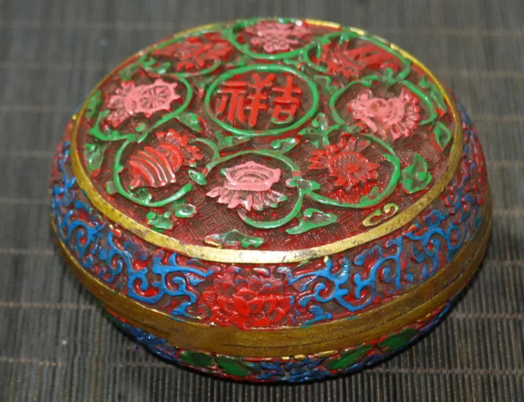 Decorative round box with floral patterns on a textured surface