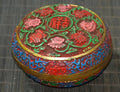 Decorative round box with floral patterns on a textured surface