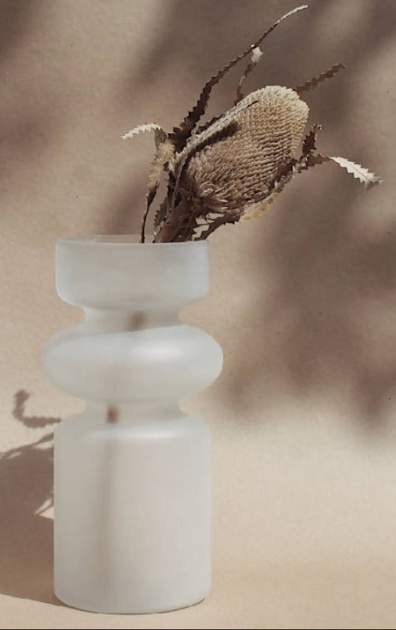 White vase with dried plant on a beige background