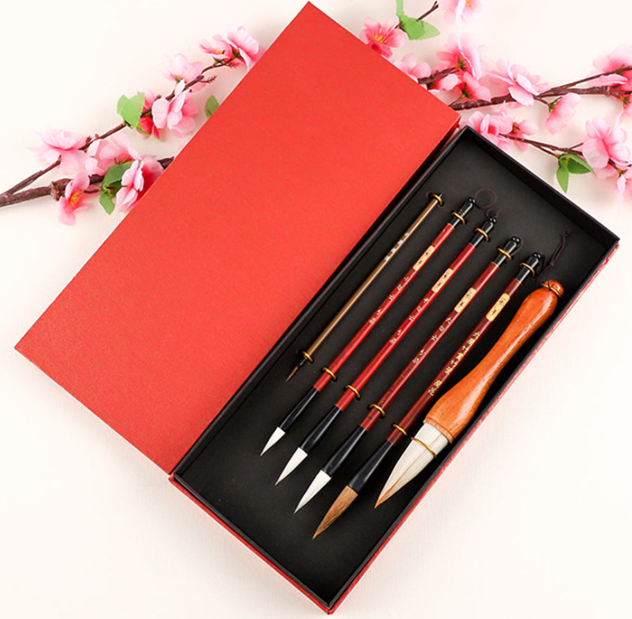 Set of paintbrushes in a red box with cherry blossom branches in the background