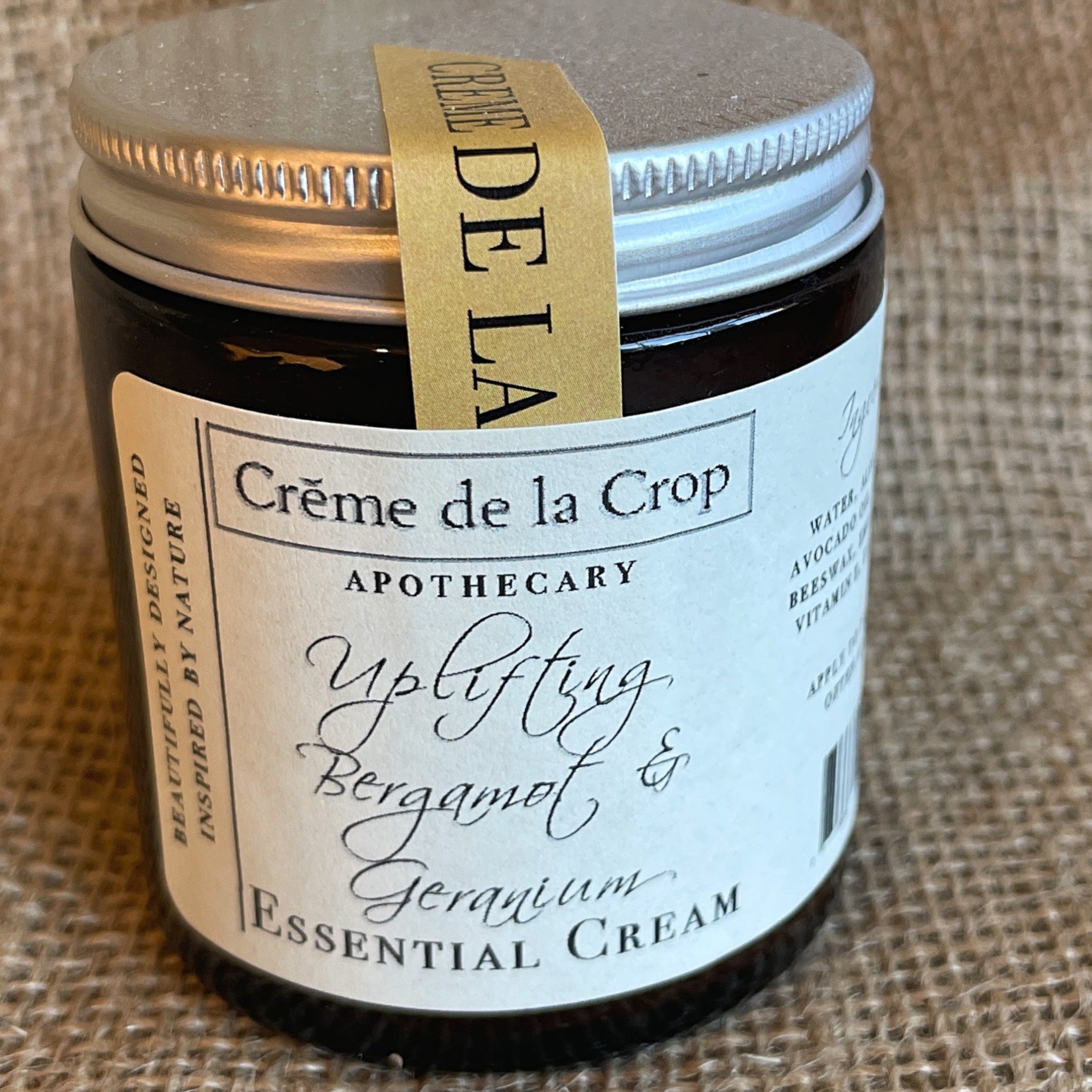 Jar of Crème de la Crop essential cream on a burlap background