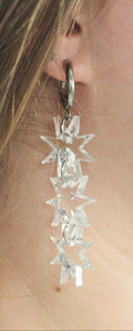 Close-up of a person wearing silver floral earrings with a blurred background