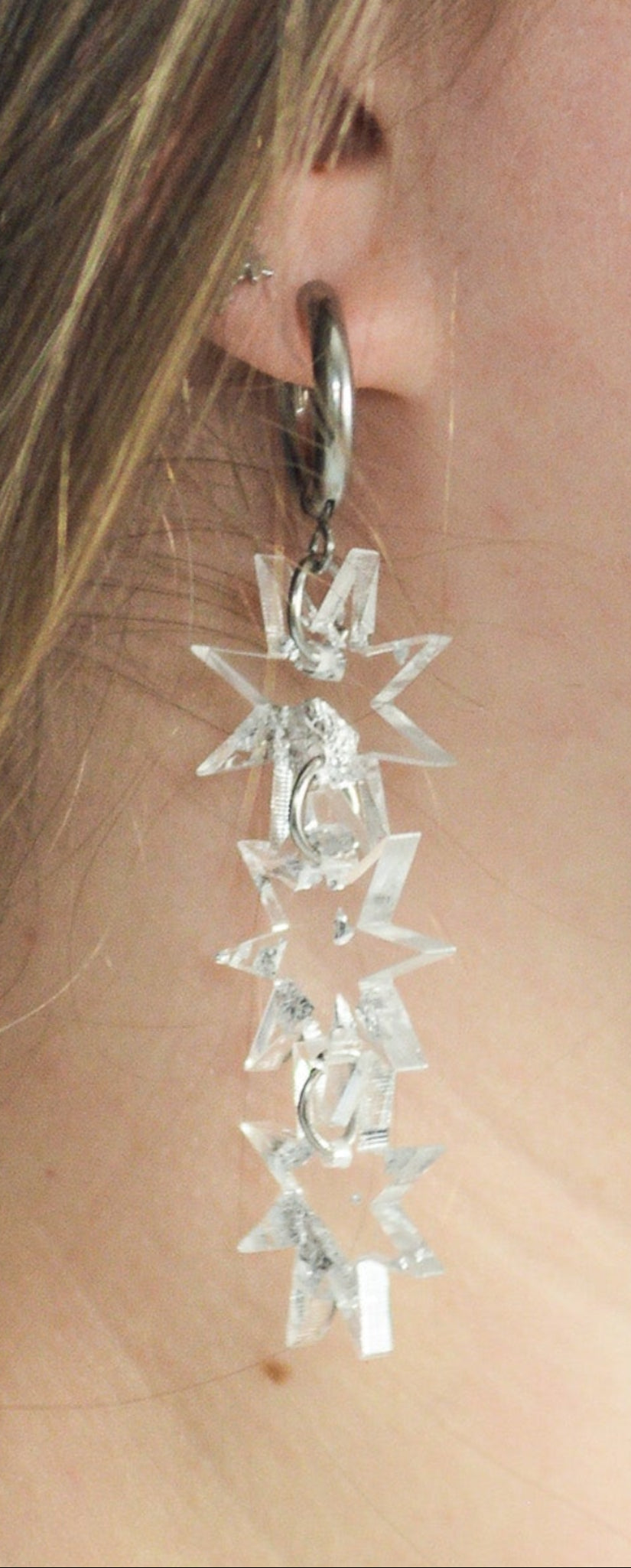 Close-up of a person wearing silver floral earrings with a blurred background