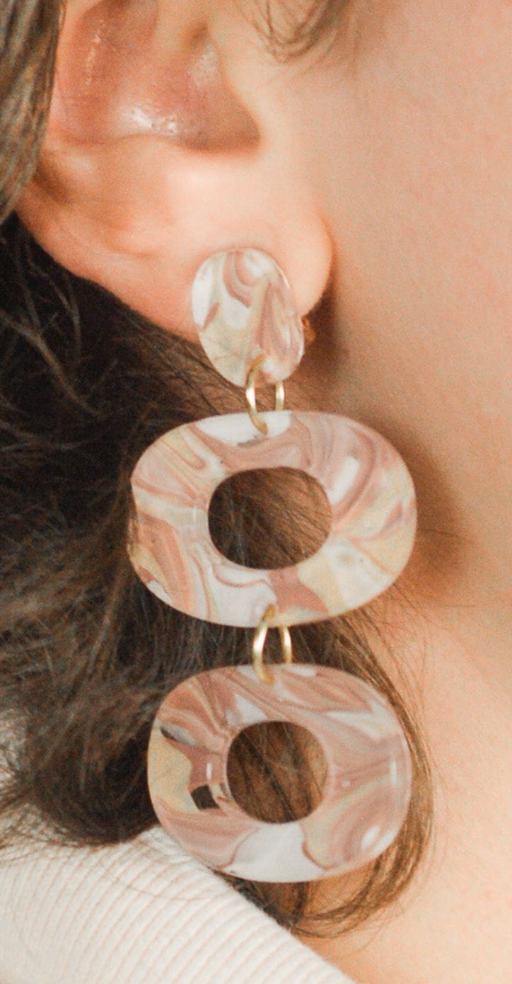 Close-up of a person wearing pink earrings with a neutral background