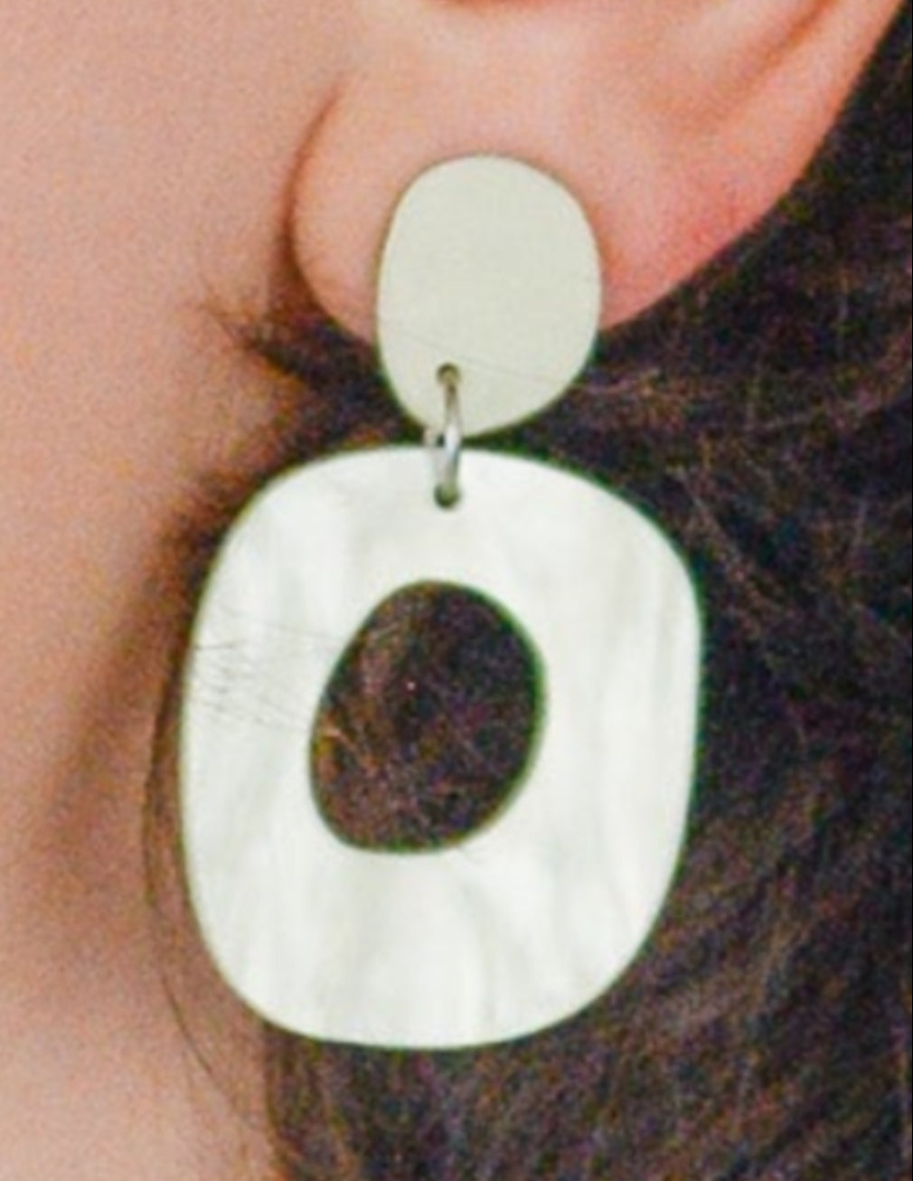 Woman wearing large hoop earrings against a light blue background