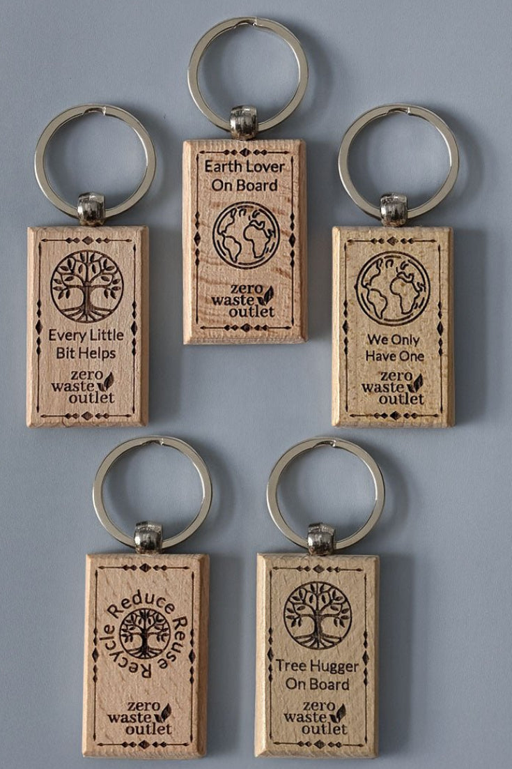 Set of five wooden keychains with environmental-themed text on a gray background