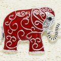 Decorative red elephant pin with silver detailing on a woven background