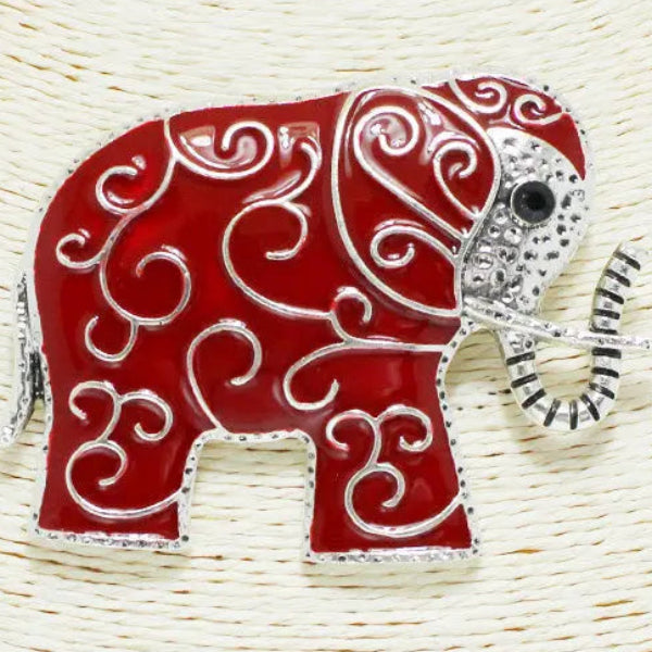 Decorative red elephant pin with silver detailing on a woven background